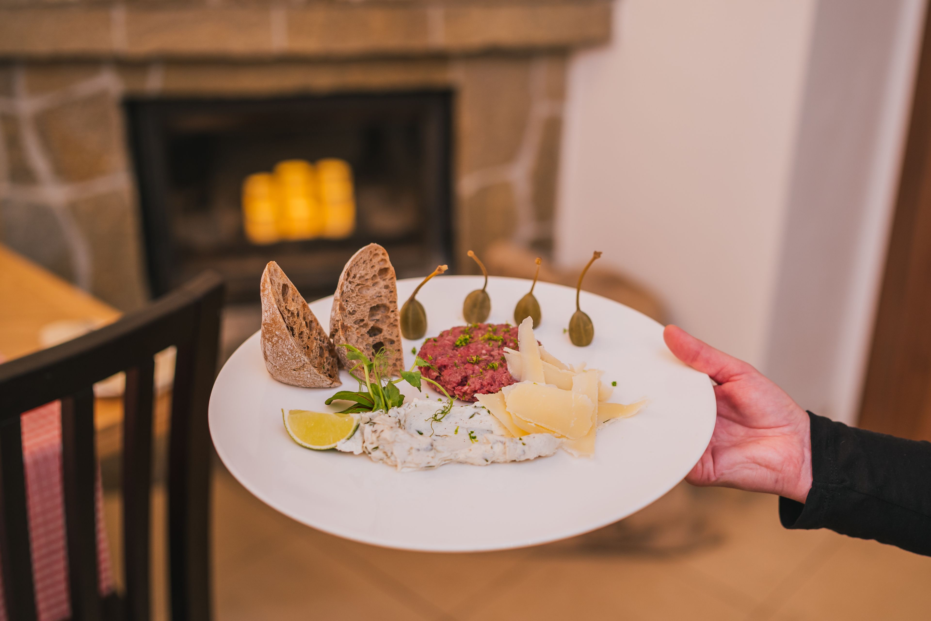 A plate of food with bread, olives, cheese, and a lime wedge.