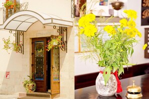 A hotel entrance with a wooden door, a sign above the door, and a flower arrangement outside. - Belleville (Iasi)