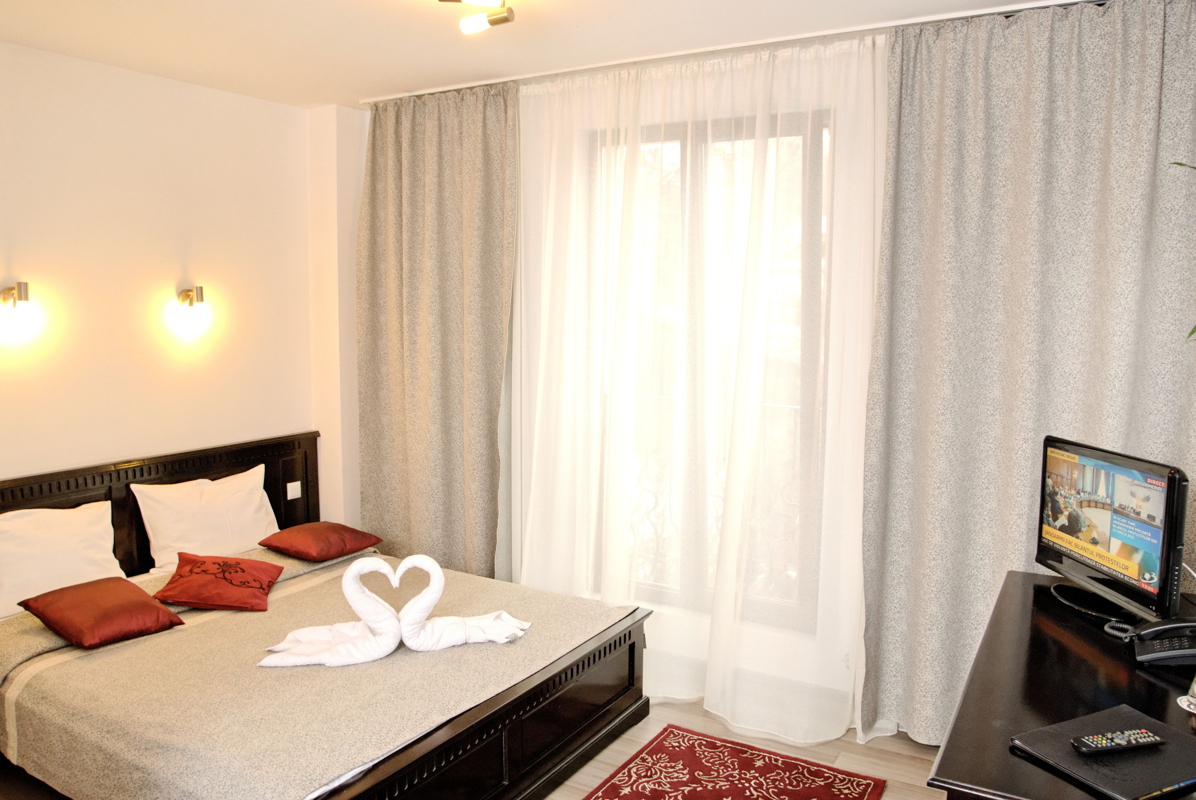 Quarto de hotel com cama, televisão e cortinas.
