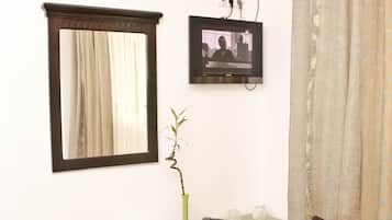 A small, well-lit room with a desk, chair, and an air conditioning unit.