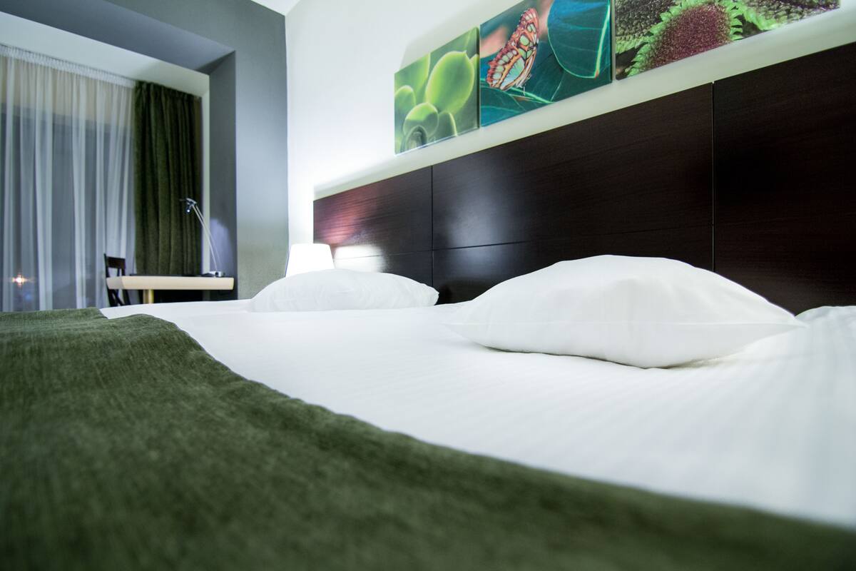 Ein Hotelzimmer mit einem Bett, einem Nachttisch, einer Lampe und einem Wandbild.