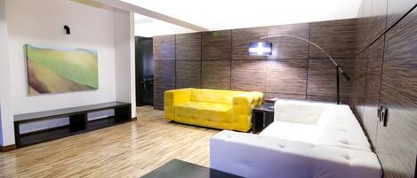 A modern living room with a yellow sofa, white sofa, and a black coffee table.