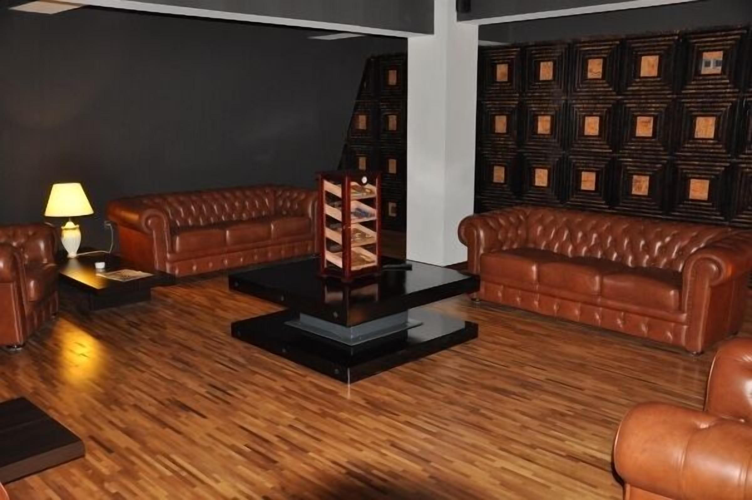 A room with two leather sofas, a glass coffee table, and a lamp on a side table.