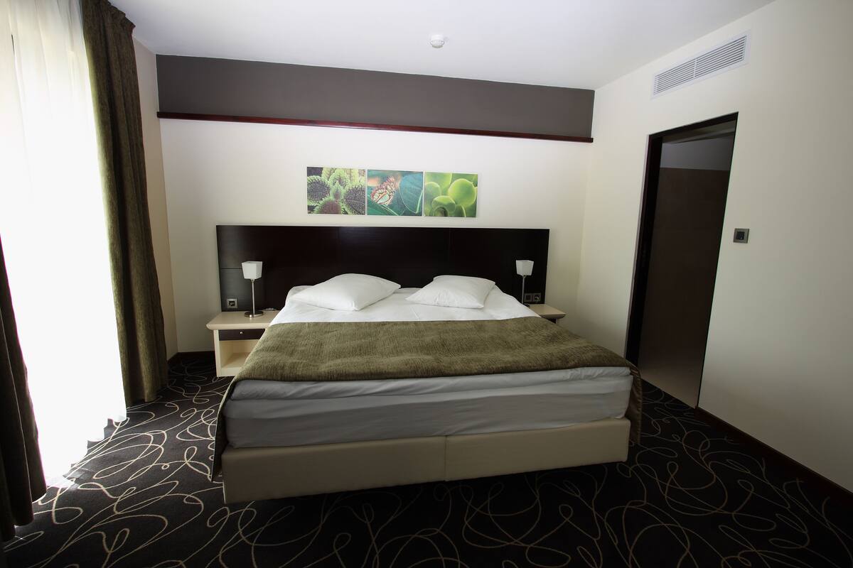 Ein Hotelzimmer mit einem großen Bett, einem Nachttisch, einer Lampe und einem Bild an der Wand.