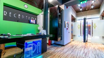 A reception area with a green wall, a neon sign, and a wooden floor.