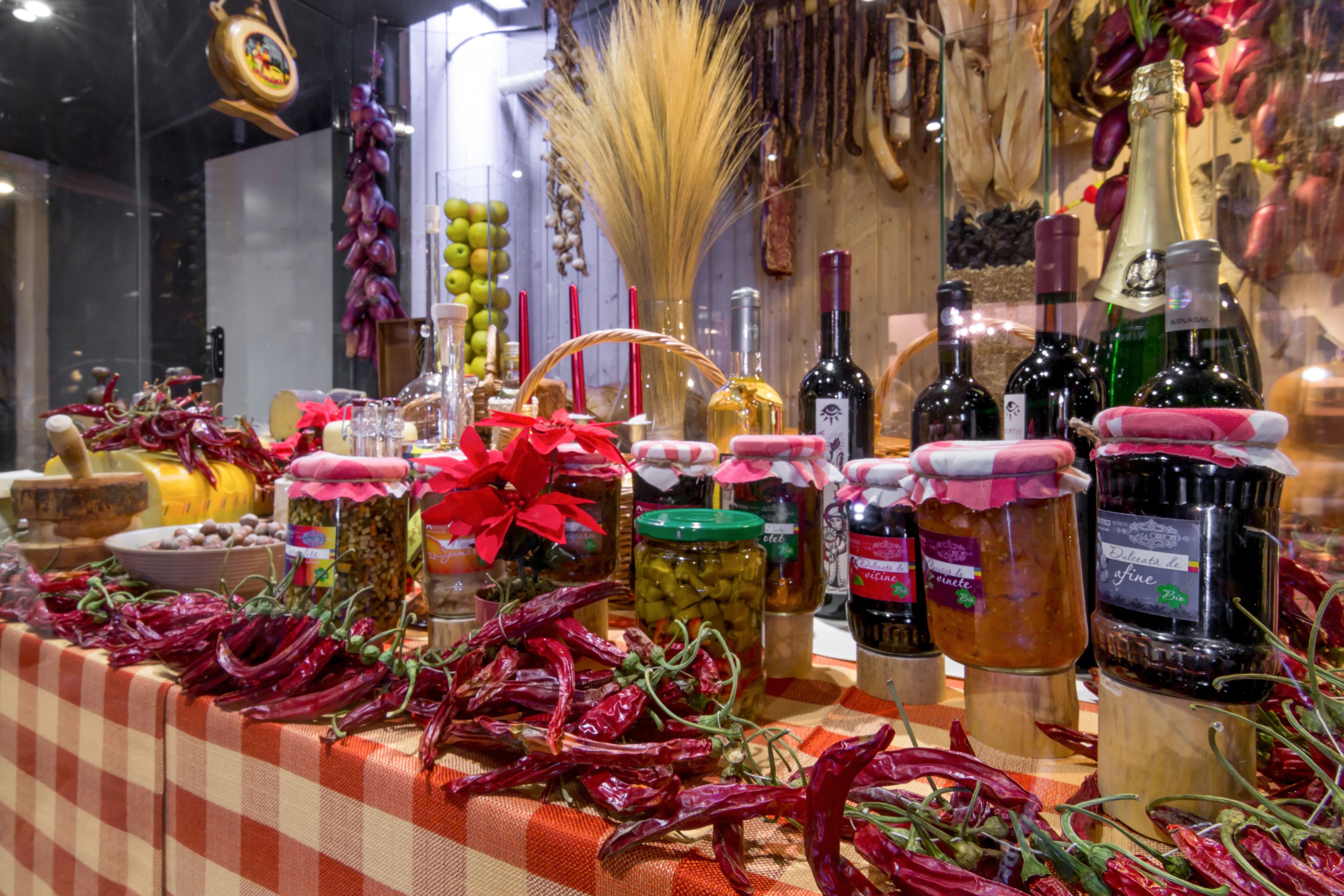 A display of various food items and condiments, including jars of pickles, bottles of wine, and dried peppers.