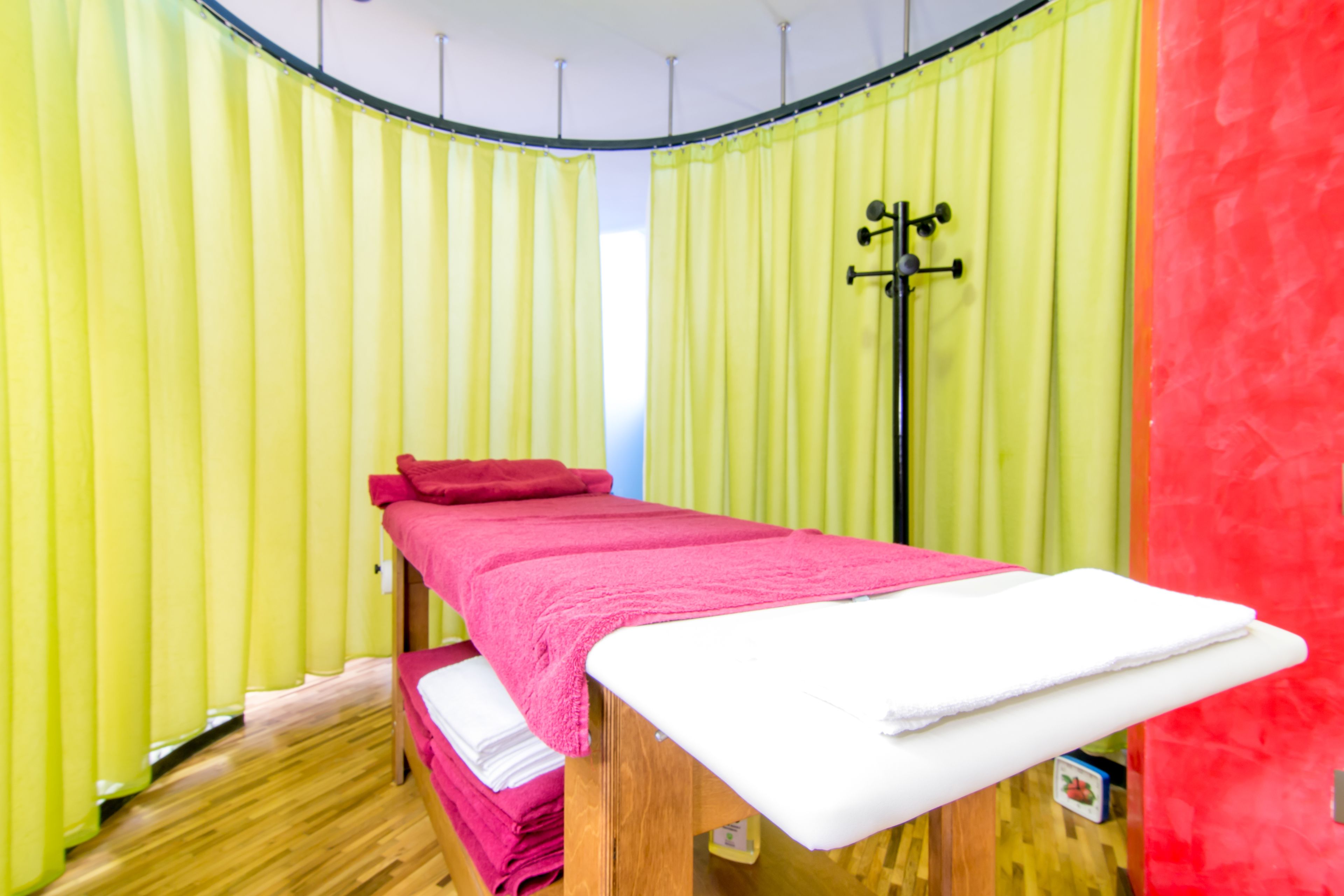 A room with a wooden bed, a red pillow, and a white mattress.