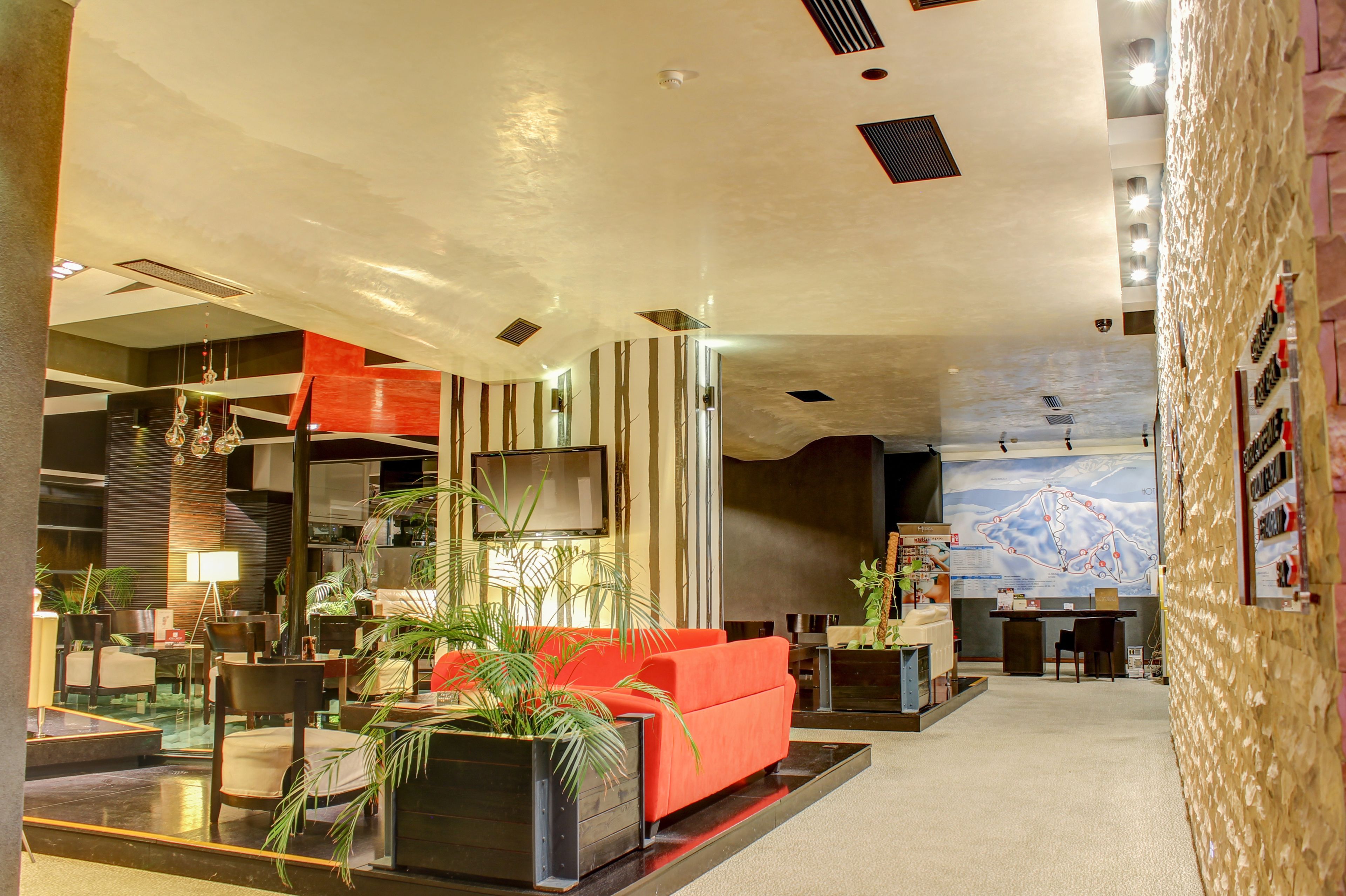 A modern lobby with a red sofa, potted plants, and a large map on the wall.