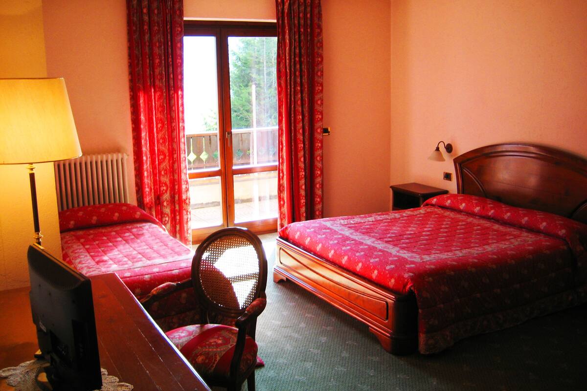 Habitación de hotel con dos camas, una silla, un escritorio, una lámpara y vistas al exterior.
