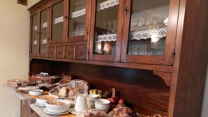 A buffet setup with various food items and a wooden cabinet with glass doors. - Hotel Panoramique (Sarre)