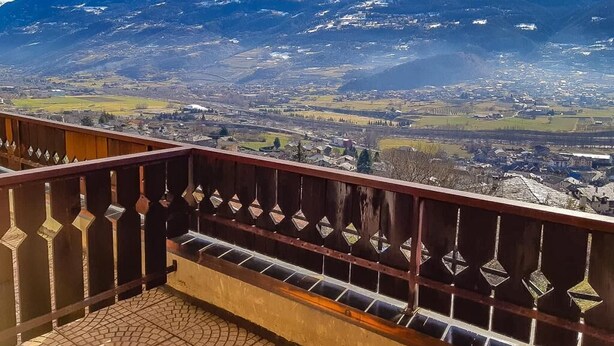 A balcony with a view of a mountainous landscape and a town below. - Hotel Panoramique (Sarre)