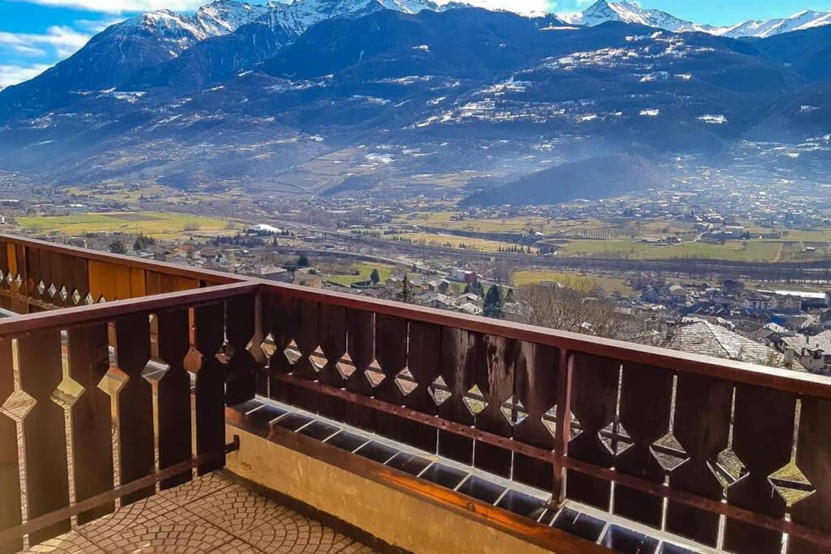 Un balcón con vistas a un paisaje montañoso y una ciudad en la falda.