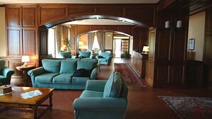 A spacious living room with a large arched doorway, wooden paneling, and a seating area with sofas and a coffee table. - Hotel Panoramique (Sarre)