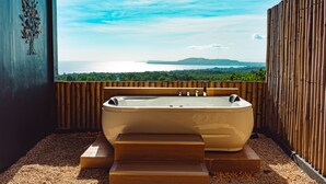Un área de spa con hidromasaje, escalones de madera y vistas al mar.