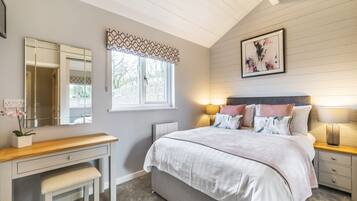 A bedroom with a bed, bedside tables, a desk, a chair, a window, and a mirror.