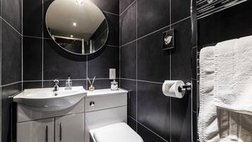 Ein modernes Badezimmer mit Waschbecken, Spiegel und Toilette in Weiß, sowie ein Handtuchhalter mit einem weißen Handtuch.