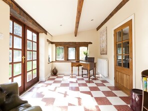 A room with a checkered floor, wooden beams on the ceiling, a desk with a vase, and a door with glass panels. - Throstle Nest Farm (Skipton)