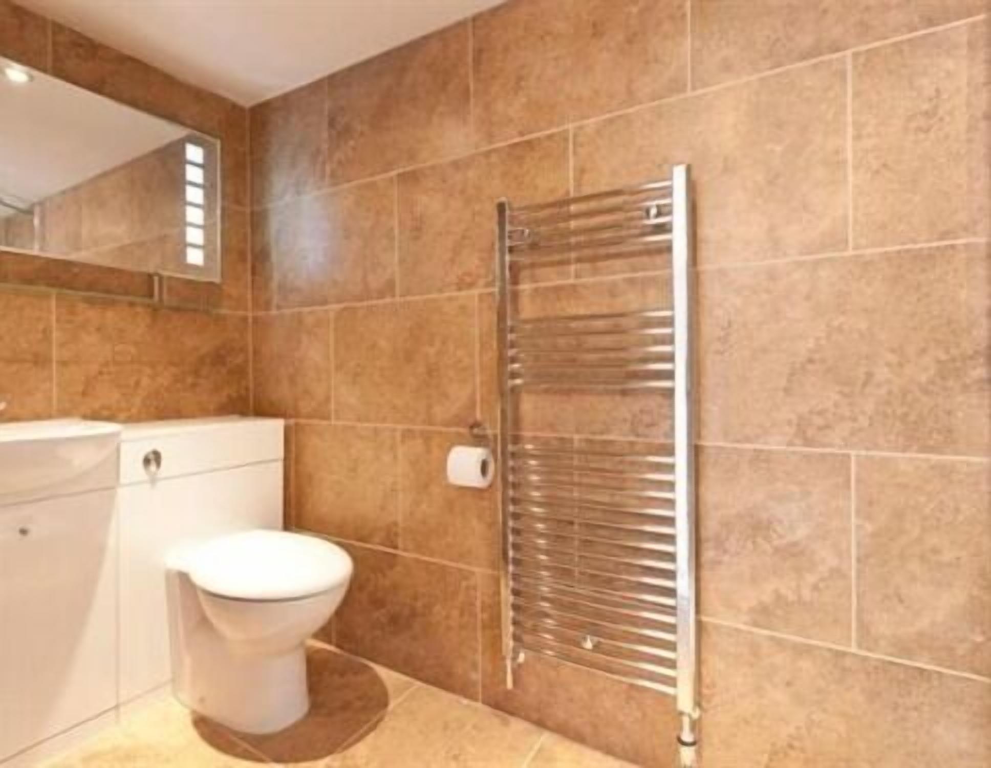 Une salle de bain avec des toilettes, un lavabo et un porte-serviettes, le tout adossé à un mur carrelé.