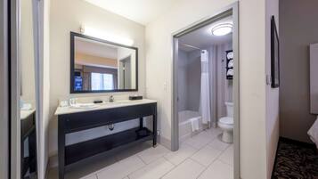 Une salle de bain moderne avec un grand miroir, un meuble-lavabo noir, une baignoire et des toilettes.