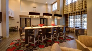 Un hall d’hôtel moderne doté d’un bar, de coins salon et de grandes fenêtres.