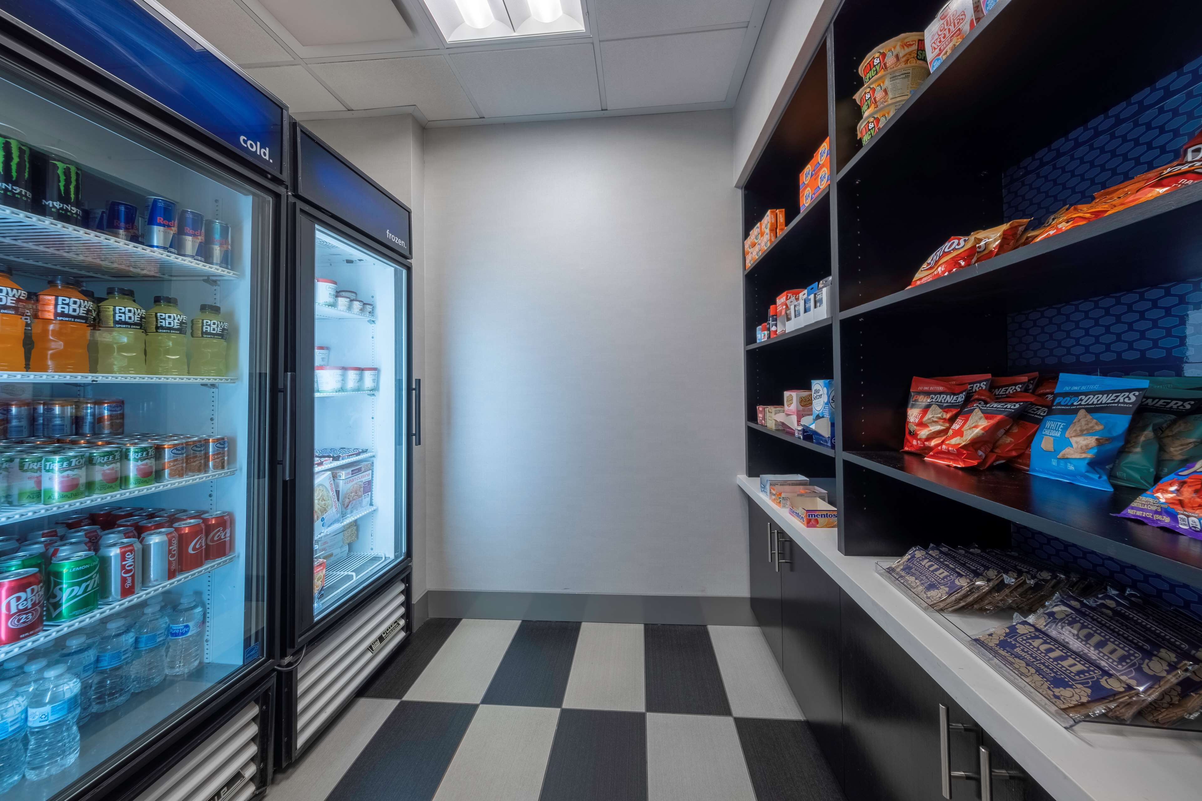 A refrigerated beverage cooler stocked with various drinks and a snack shelf with packaged snacks.