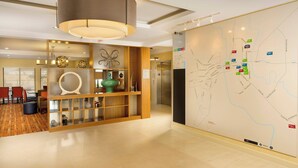 A hotel lobby with a map on the wall, a reception desk, and a seating area with chairs and ottomans.