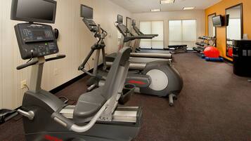 A gym with treadmills, elliptical machines, and exercise balls.