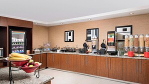 A modern kitchen with granite countertops, wooden cabinets, and various appliances including a coffee machine and a food dispenser.