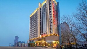 A multi-story hotel with a modern design, featuring a prominent entrance and a large glass facade.