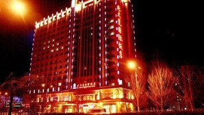 Un hotel de varios pisos con señalización iluminada y una entrada destacada.