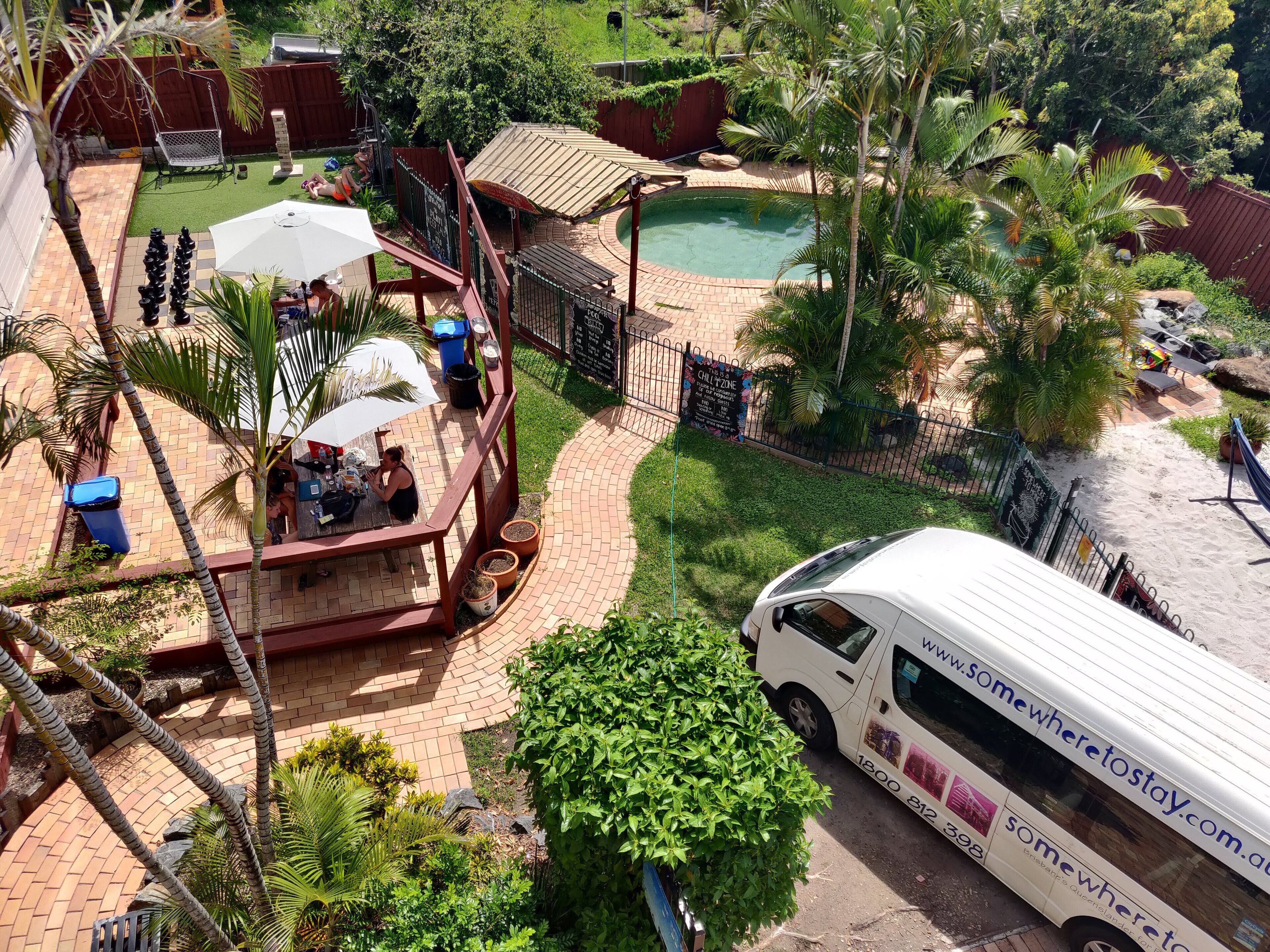 Un área de piscina con jacuzzi, sillones de descanso y una zona de estar cubierta.