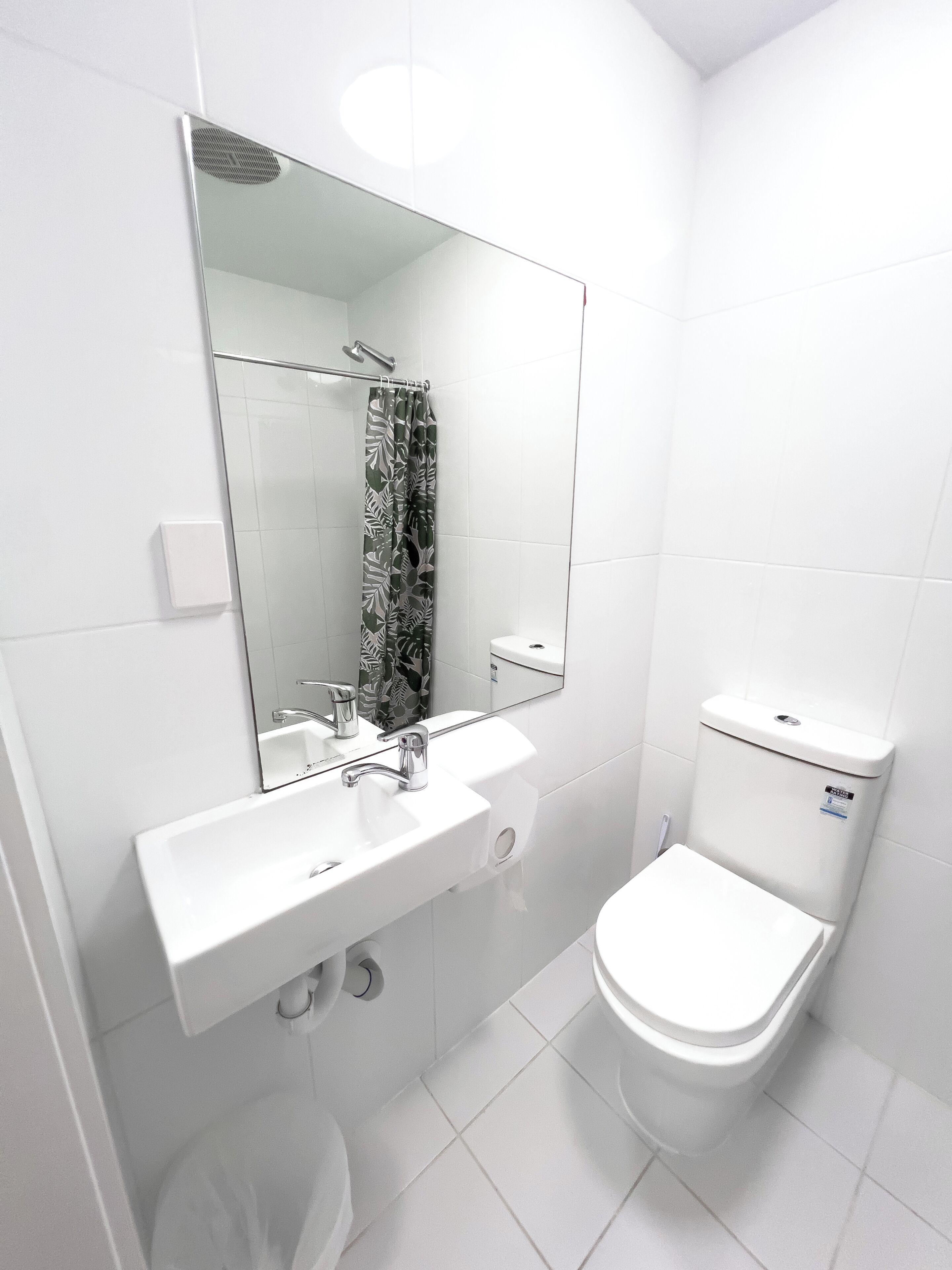 Un baño moderno con lavamanos, espejo y retrete blancos.