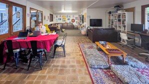 A spacious living room with a red table, multiple seating options, a television, and a bookshelf. - Somewhere To Stay Backpackers (Highgate Hill)