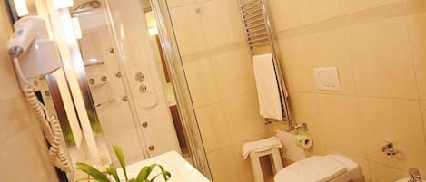 A modern bathroom with a glass-enclosed shower, a white sink, a toilet, and a bidet.