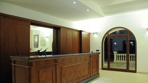 Una zona de recepción con un mostrador de madera, un espejo grande y una puerta que da a un balcón.