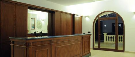 A reception area with a wooden counter, a large mirror, and a door leading to a balcony.