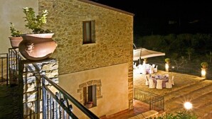 A stone building with a balcony, outdoor seating area, and potted plants. - Casale del Golfo (Alcamo)