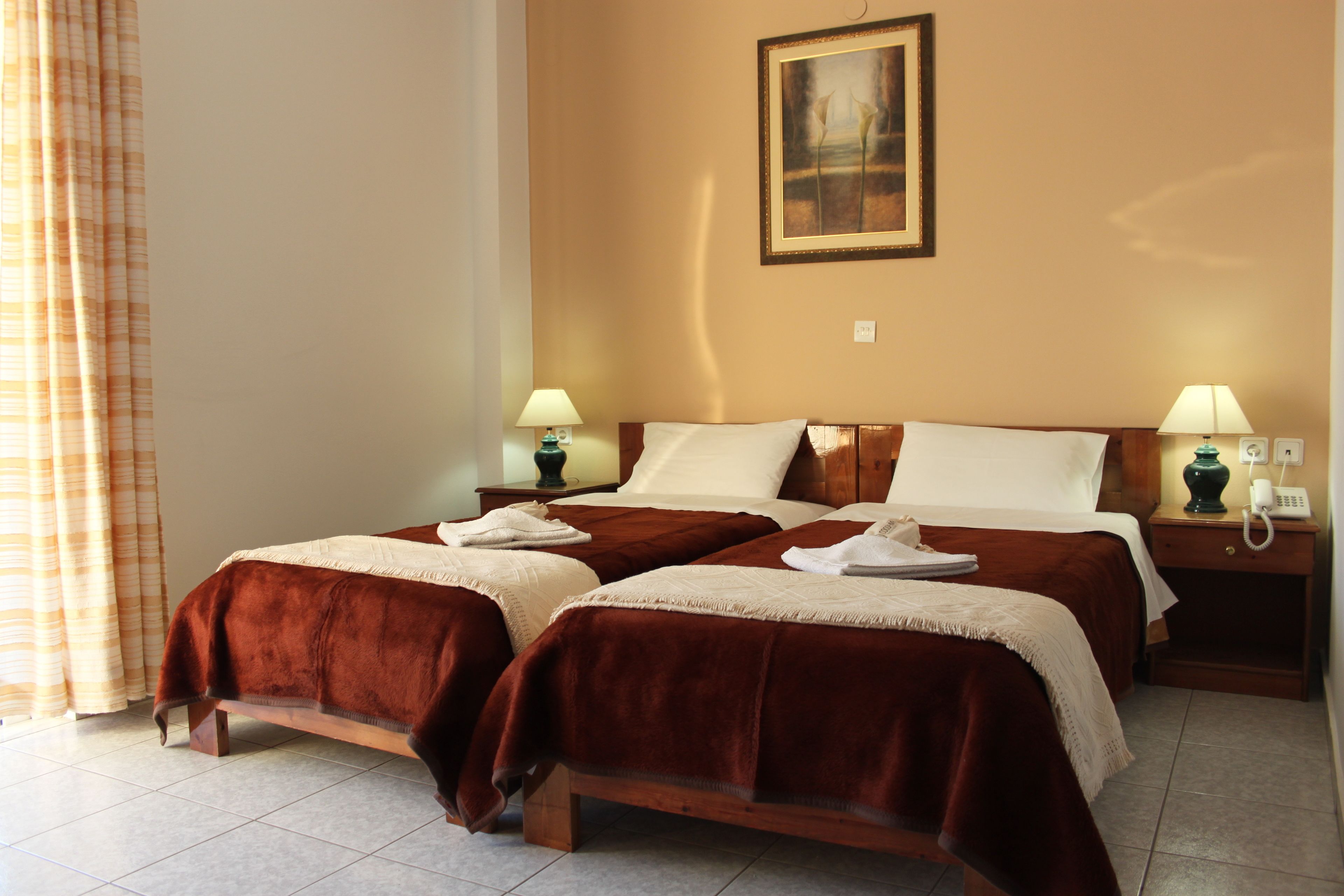 Une chambre d’hôtel avec deux lits, un tableau au mur et deux tables de chevet avec des lampes.