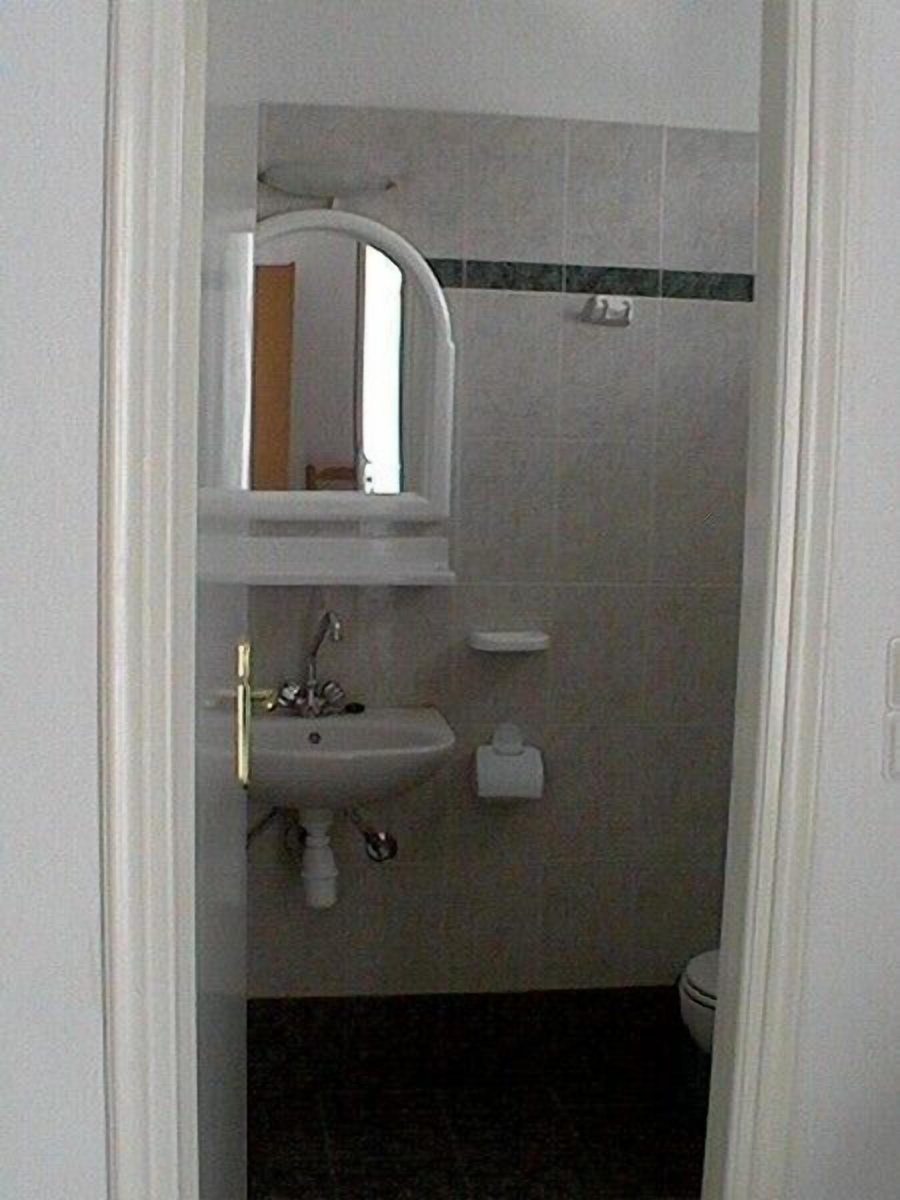 Une petite salle de bain avec un lavabo, un miroir et des toilettes.
