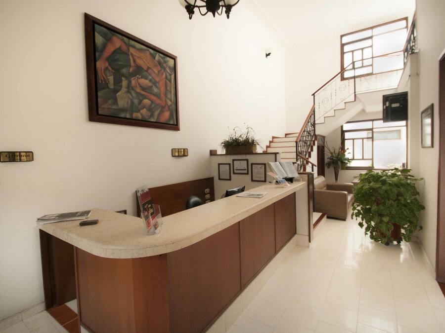 Un área de recepción con un mostrador de madera, una escalera y un cuadro grande en la pared.
