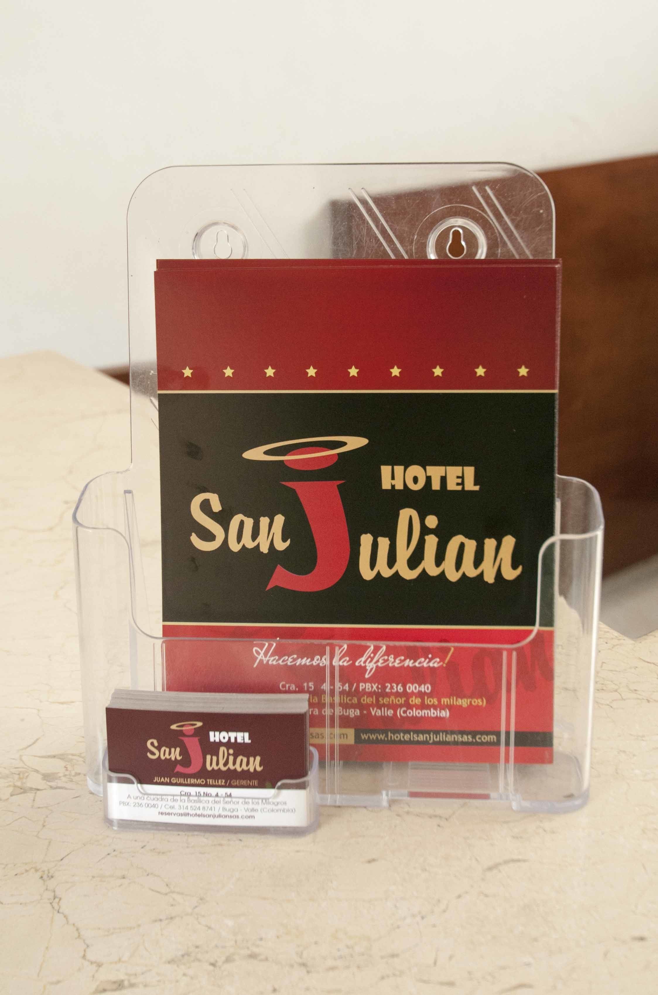 A Hotel San Julian promotional display with a clear plastic stand, a business card, and a website URL.