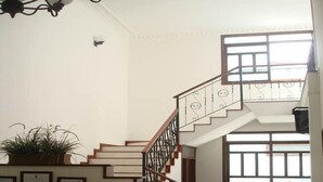 A spacious living area with a staircase, a sofa set, and a kitchen counter. - Hotel San Julian (Guadalajara de Buga)