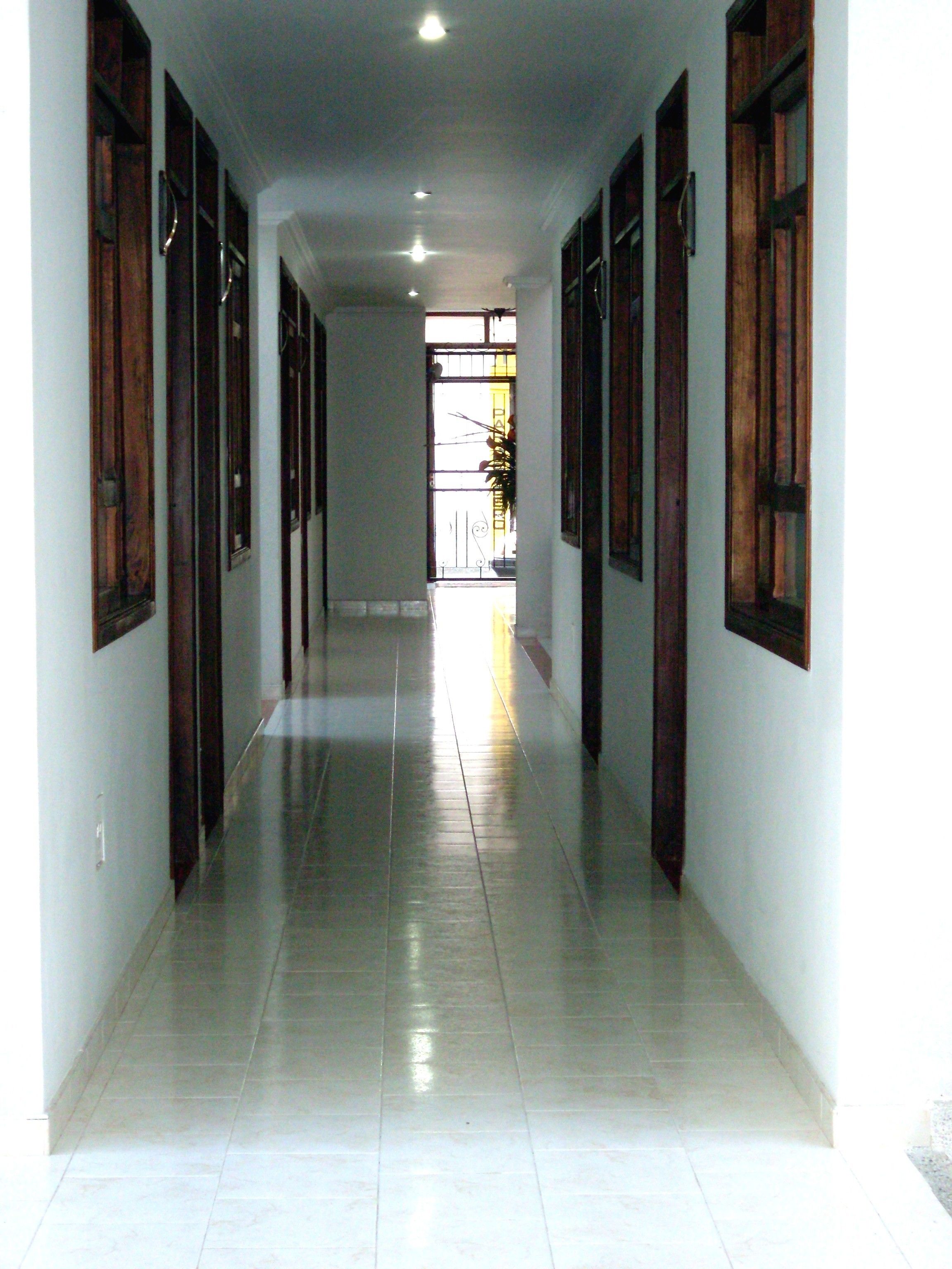 A long, narrow hallway with tiled floors and wooden doors on both sides.