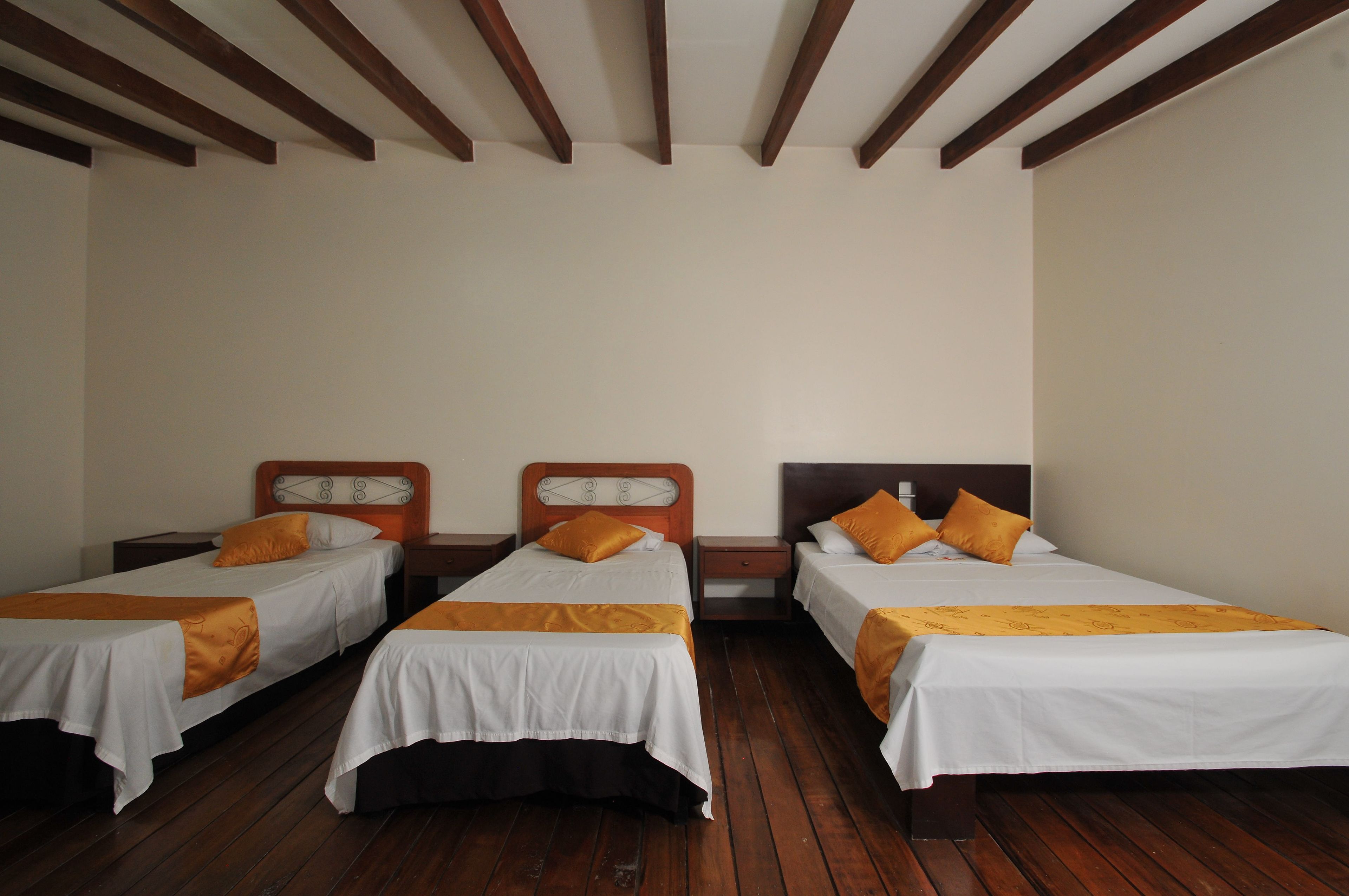 A room with three single beds, wooden floors, and a simple, clean design.