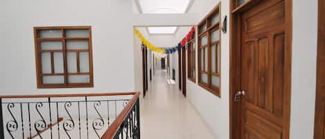 A corridor with a skylight, wooden doors, and a railing.