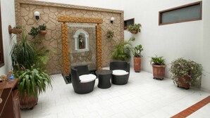 A patio area with wicker furniture, potted plants, and a decorative stone wall. - Hotel San Julian (Guadalajara de Buga)
