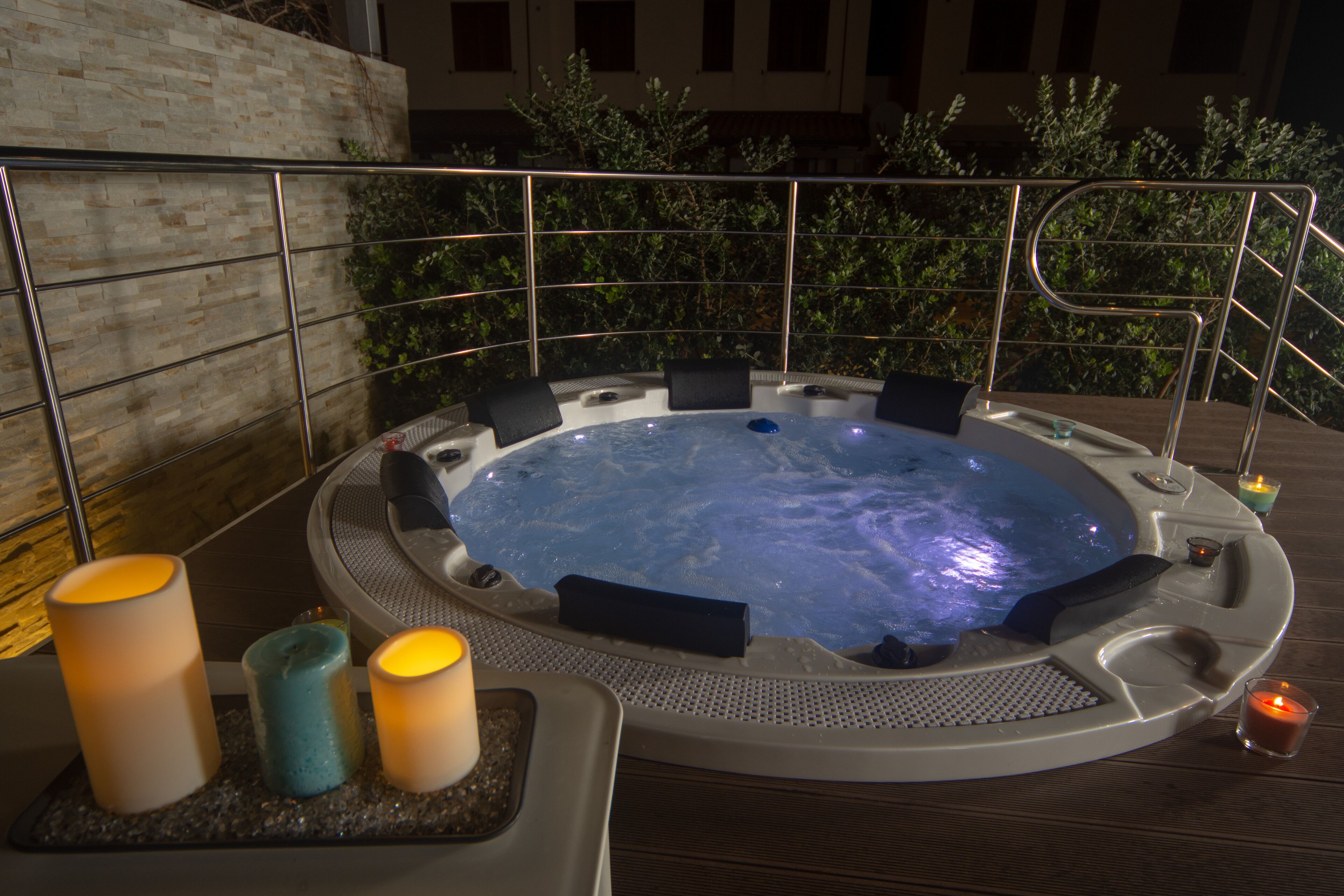 A hot tub with seating around it, candles, and a railing.