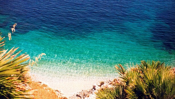 A beach with clear turquoise water, sandy shore, and some vegetation. - Room & Breakfast Aloe (San Vito Lo Capo)