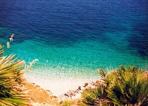 A beach with clear turquoise water, sandy shore, and some vegetation. - Room & Breakfast Aloe (San Vito Lo Capo)