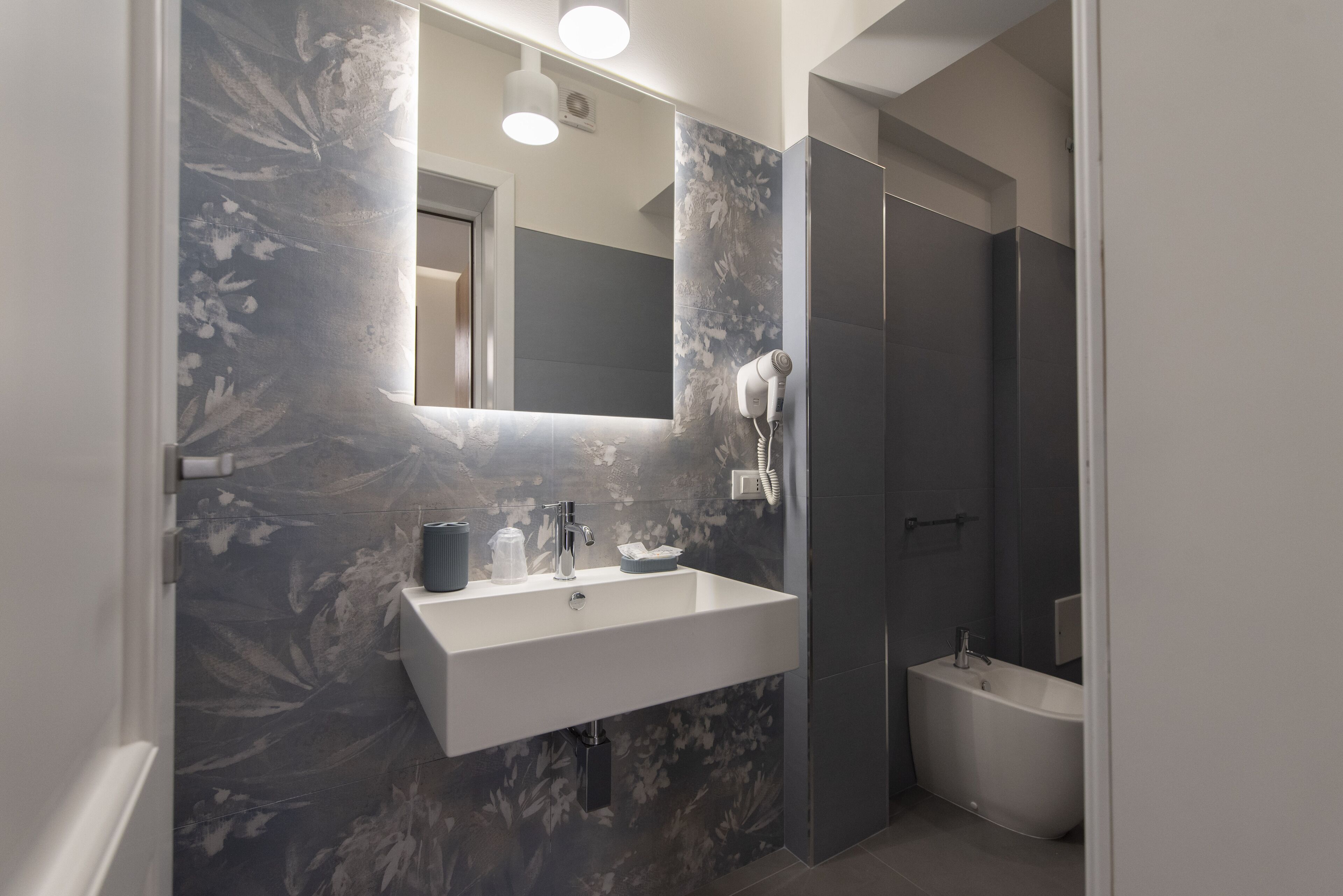 A modern bathroom with a white sink, a mirror, and a bathtub.